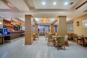 Un restaurante con mesas y sillas y un bar. en Pefka Hotel, en Tesalónica