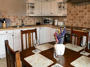 a kitchen with a wooden table with a vase of flowers at Foal Barn Cottages - Hayloft - Spennithorne in Middleham