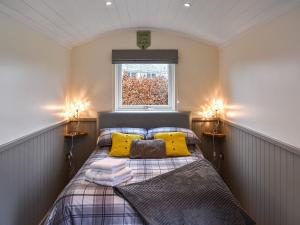Un dormitorio con una cama con almohadas amarillas y una ventana. en Greengill Farm Shepherds Hut- Ukc3632, en Gilcrux