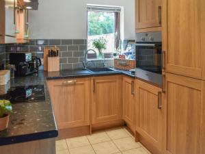 a kitchen with wooden cabinets and a sink at Rowan Cottage in Northrepps