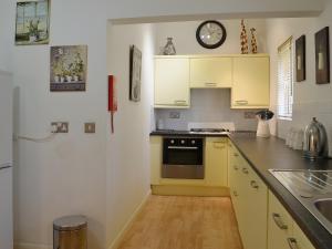 a kitchen with yellow cabinets and a clock on the wall at High Moor Cottage in Dufton