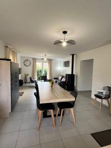 Una cocina y una sala de estar con una mesa y sillas de madera. en Gîte neuf, à 12mn du Futuroscope, à la campagne-Le Coquelicot, en Saint-Léger