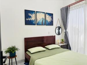 - une chambre avec un lit et trois peintures murales dans l'établissement Nhà mình Homestay, à Ấp Thanh Sơn (1)