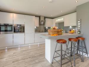 a kitchen with white cabinets and bar stools at Ivy Cottage in Beck Hole