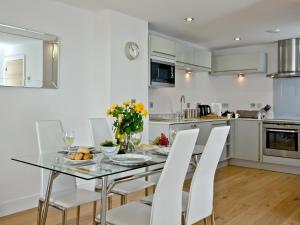 een keuken en eetkamer met een glazen tafel en witte stoelen bij 4 Ocean Point in Croyde