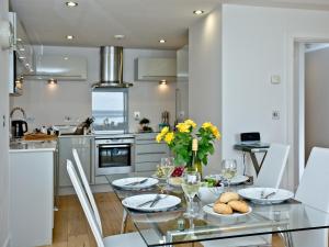 een keuken met een glazen tafel met eten erop bij 4 Ocean Point in Croyde