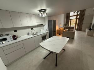 a kitchen with white cabinets and a table in it at Royal Loft Residence in Târgu Jiu