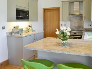 a kitchen with green chairs and a vase of flowers on a counter at Swallows Retreat in Hartland