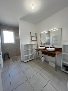 Un baño con dos lavabos y un espejo. en Gîte neuf, à 12mn du Futuroscope, à la campagne-Le Coquelicot, en Saint-Léger
