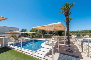 a pool with an umbrella and a palm tree at Family-friendly apartments with swimming pool Novalja, Pag - 14275 in Novalja +19 photos