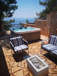 eine Terrasse mit zwei Stühlen und einem Whirlpool in der Unterkunft Secluded fisherman's cottage Cove Golubinka, Hvar - 14344 in Zastražišće