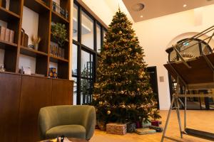 Un árbol de Navidad en una habitación con una silla y un piano en DoubleTree by Hilton Sittard, en Sittard