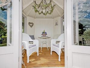 a porch with white wicker chairs and a table at The Mains in Keldhead