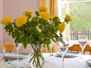a vase of yellow roses sitting on a table with glasses at Eagles Gate Lodge in Banff +32 photos
