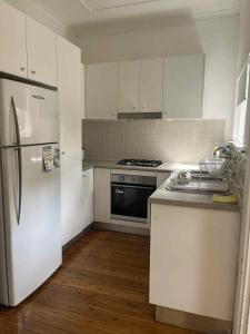 une cuisine avec des armoires blanches et un réfrigérateur dans l'établissement A Cosy Private Corner in the City, à Sydney