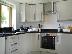 a kitchen with white cabinets and a stove top oven at Little Barn in Gilwern