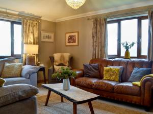 LlanwrdaにあるMaes Y Bryn Farmhouseのリビングルーム(茶色の革張りのソファ、椅子付)