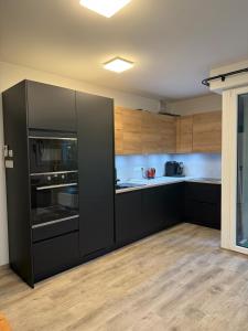 a kitchen with black appliances and wooden cabinets at Modern Apartment in a Leafy Town Close to Prague 