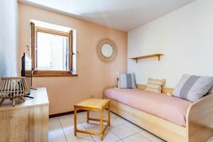 a bedroom with a bed and a table and a window at Typical stone house with balcony in Ossuccio +12 photos