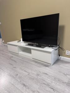 een flatscreen-tv zittend op een wit entertainment center bij Warm apart in Kouvola