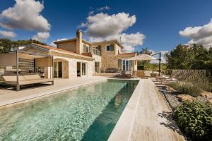 a house with a swimming pool in front of a house at Villa Mila with private pool, BBQ and jacuzzi in Strpačići