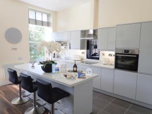 a kitchen with white cabinets and a large island with chairs at The Haven in Scarborough