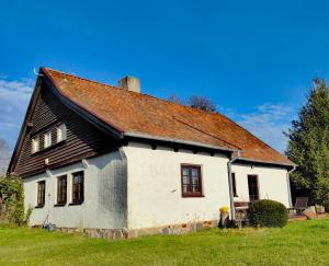 an old white house with a brown roof at Na Żurawim Wzgórzu in Pasym