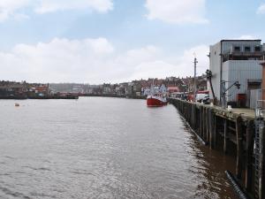 a river with a red boat in the water at Seacrest Cottage in Whitby +4 photos