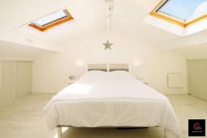 1 dormitorio con 1 cama blanca en una habitación con tragaluces en Duplex Biscarrosse plage pour 4 Personnes, en Biscarrosse