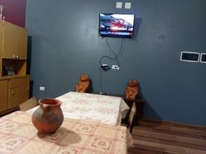 a dining room with a table and a tv on the wall at Hospedaje TAWA WASI in Huacalera