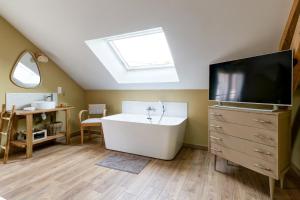 a bathroom with a bath tub and a television at L'atelier de Théo - Jacuzzi Privé in Chaourse-en-Thiérache