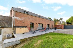 a brick building with a patio with tables and chairs at L'atelier de Théo - Jacuzzi Privé in Chaourse-en-Thiérache