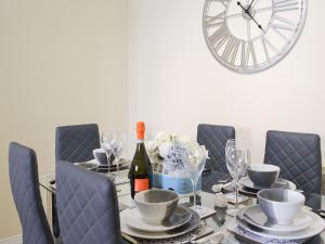 - une table à manger avec une bouteille de vin et une horloge dans l'établissement Newcombe Cottage, à Flamborough