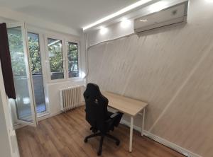 Un escritorio con una silla en una habitación con ventanas. en Nela Lux, en Belgrado