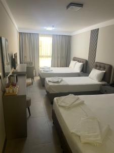 a hotel room with three beds and a window at Grand Cennet Beach Hotel in Akcay