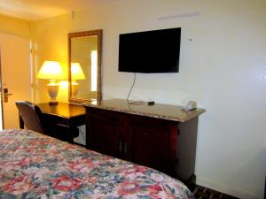 Habitación de hotel con cama, escritorio y TV. en Budget Host Inn, en Arlington