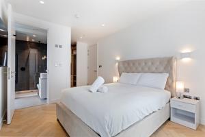 een slaapkamer met een groot wit bed en een badkamer bij Stylish Flat-Leisure Pool & Gym in Londen
