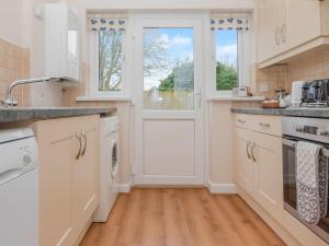 a kitchen with white cabinets and a door at Oyster Catchers - Uk6730 in Lydstep
