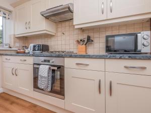 a kitchen with white cabinets and a microwave at Oyster Catchers - Uk6730 in Lydstep