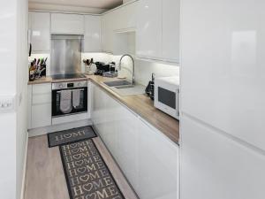 リトルハンプトンにあるLamornaの白いキャビネットとキッチンラグ付きのキッチン +28枚の写真