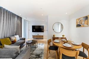 een woonkamer met een bank en een tafel bij Stylish Flat-Leisure Pool & Gym in Londen