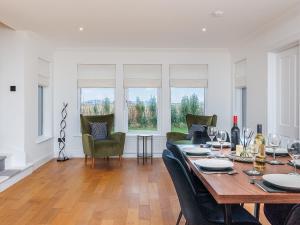 een eetkamer met een tafel, stoelen en ramen bij Sealladh Na Mara in Pollachar