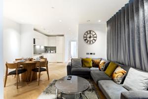 een woonkamer met een bank en een tafel bij Stylish Flat-Leisure Pool & Gym in Londen