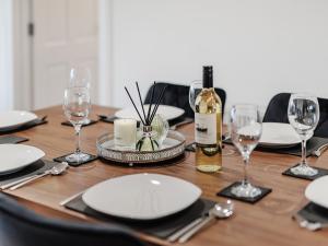 een houten tafel met borden en glazen en een fles wijn bij Sealladh Na Mara in Pollachar