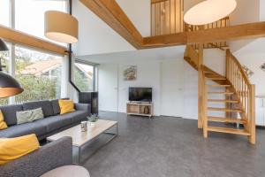 a living room with a couch and a staircase at Zonnedorp 22 Vakantiehuis Anoes Renesse | Strandnabij Comfort in Zeeland in Renesse