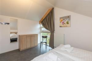 a bedroom with a bed and a desk and a chair at Zonnedorp 22 Vakantiehuis Anoes Renesse | Strandnabij Comfort in Zeeland in Renesse