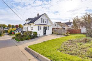a white house with a black roof on a street at 1 Mi to Downtown Dubuque! Spacious Home in Dubuque