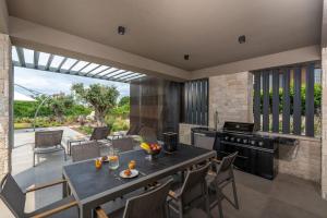 an outdoor kitchen with a table and a stove at Villa Visignano with private pool, BBQ and jacuzzi in Strpačići
