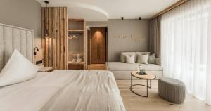 a bedroom with a large white bed and a table at Forster's Naturresort in Neustift im Stubaital