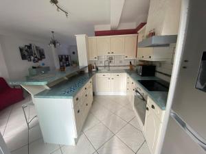 una cocina con armarios blancos y encimeras azules en L'Hippodrome d'Arras - Appartement 3 chambres, en Arras